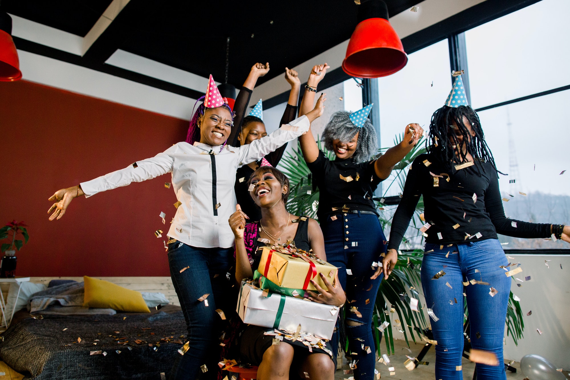 Happy African American friends girls under falling confetti at the birthday party